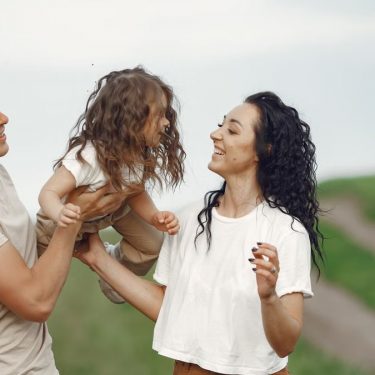 A joyful family moment outdoors with parents playing with their daughter.