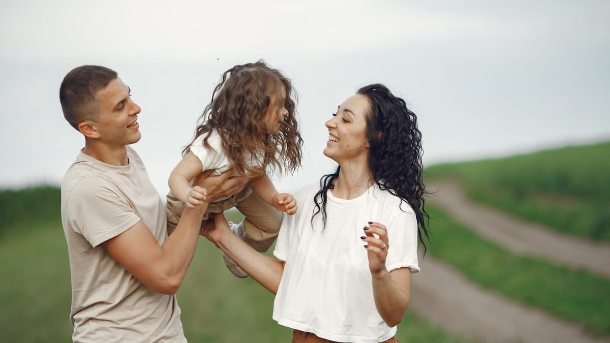 A joyful family moment outdoors with parents playing with their daughter.