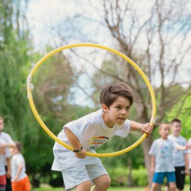 Kids enjoying a summer day playing with hula hoops in a park, showcasing friendship and fun.